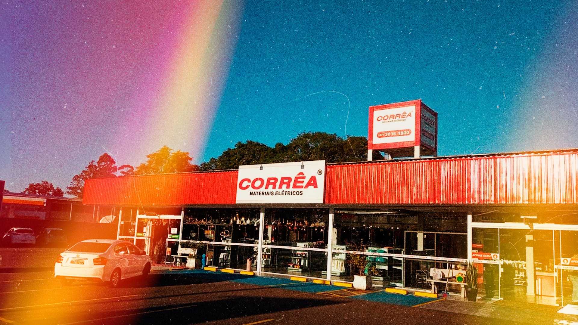 Foto frontal da Corrêa Materiais Elétricos. Na parte superior do prédio uma fachada vermelha com placa uma placa branca com Corrêa em vermelho.