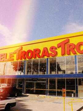 Foto frontal da Eletrorastro. Na parte superior do prédio uma fachada amarela com letreiro Eletrorastro em vermelho.