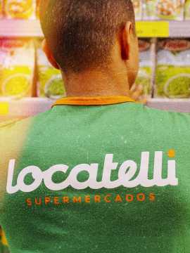 Colaborador do Locatelli, de costas, arrumando a prateleira.